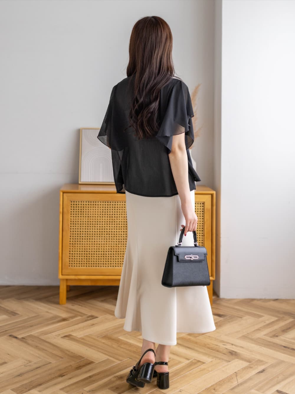 ブラック系のパンプス、ホワイト系のスカート、ブラック系のハンドバッグを着用したレディースの夏コーディネートの6枚目の写真