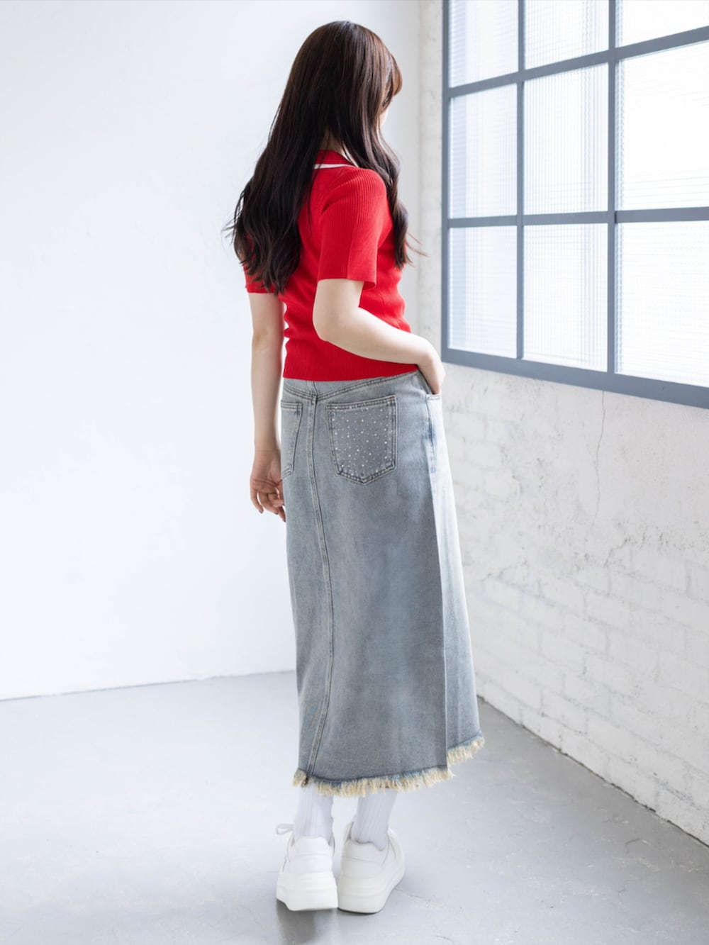 ホワイト系のスニーカー、レッド系のニット/セーター、ブルー系のスカートを着用したレディースの春コーディネートの3枚目の写真