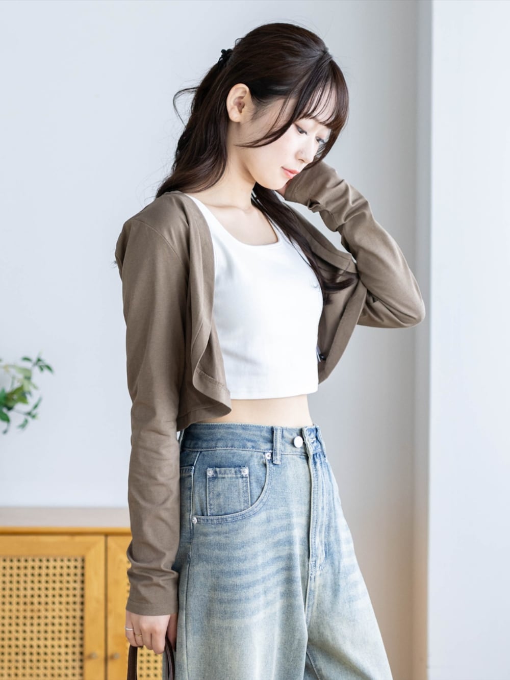 ブラウン系のショルダーバッグ、ブルー系のデニムパンツ、ブラウン系のカーディガン/ボレロを着用したレディースの夏コーディネートの5枚目の写真