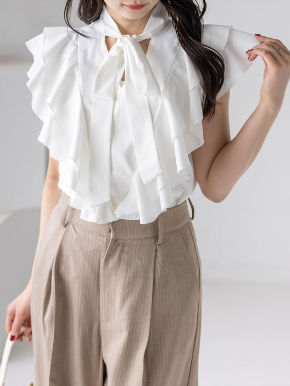 ベージュ系のスラックス、ホワイト系のハンドバッグ、ホワイト系のパンプスを着用したレディースの夏コーディネートの6枚目の写真