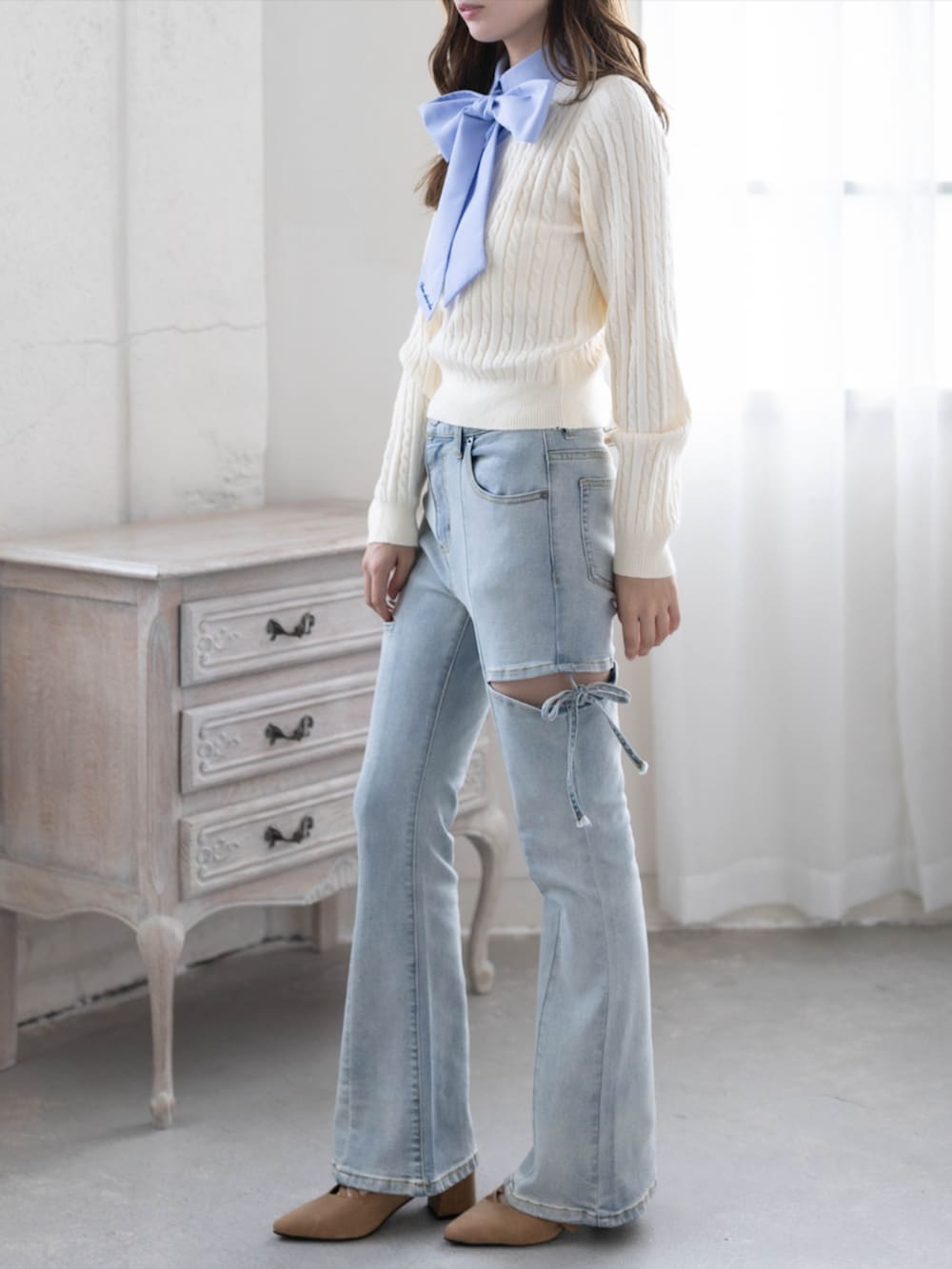 ブルー系のデニムパンツ、イエロー系のパンプス、ホワイト系のニット/セーターを着用したレディースの秋コーディネートの2枚目の写真