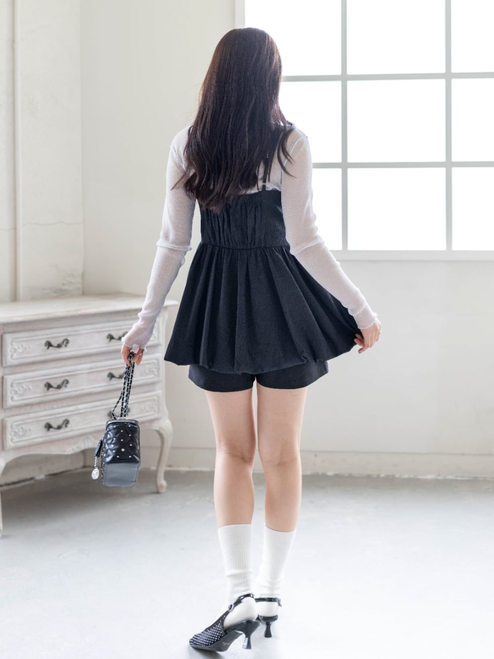 グレー系のTシャツ/カットソー、ブラック系のチュニック、ブラック系のパンプスを着用したレディースの春コーディネートの2枚目の写真