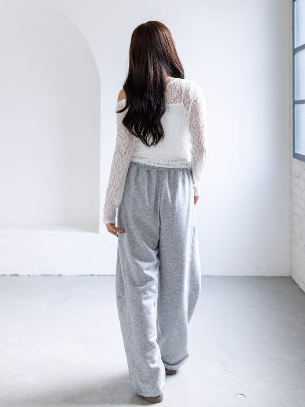 ホワイト系のスニーカー、グレー系のスウェットパンツ、ホワイト系のアンサンブルを着用したレディースの春コーディネートの2枚目の写真