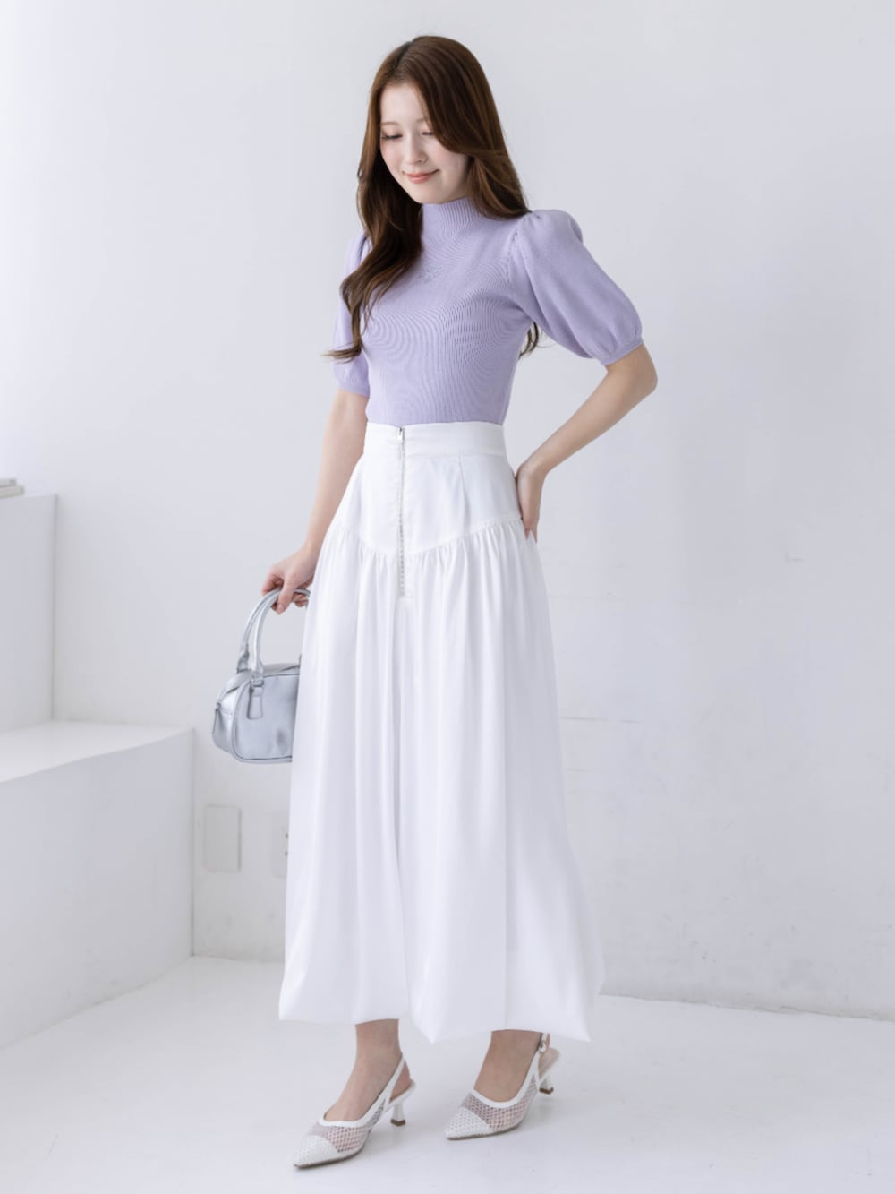 ホワイト系のスカート、ホワイト系のパンプス、パープル系のニット/セーターを着用したレディースの春コーディネートの2枚目の写真