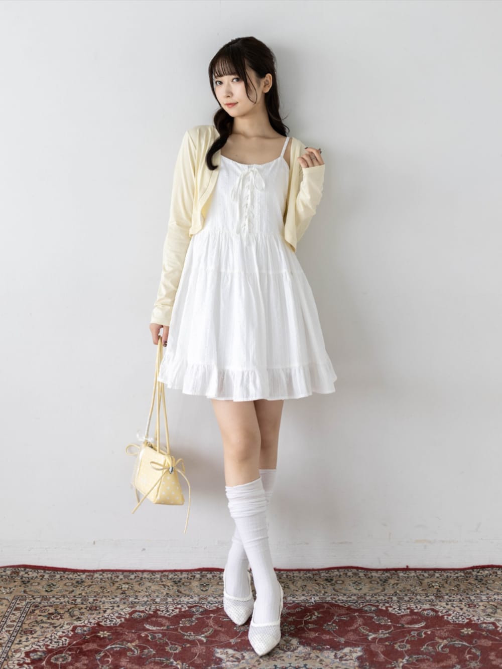 ホワイト系のワンピース、ホワイト系のパンプス、イエロー系のカーディガン/ボレロを着用したレディースの夏コーディネートの2枚目の写真