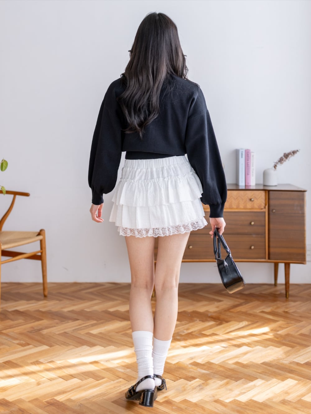 ブラック系のパンプス、ホワイト系のスカート、ブラック系のカーディガン/ボレロを着用したレディースの夏コーディネートの3枚目の写真