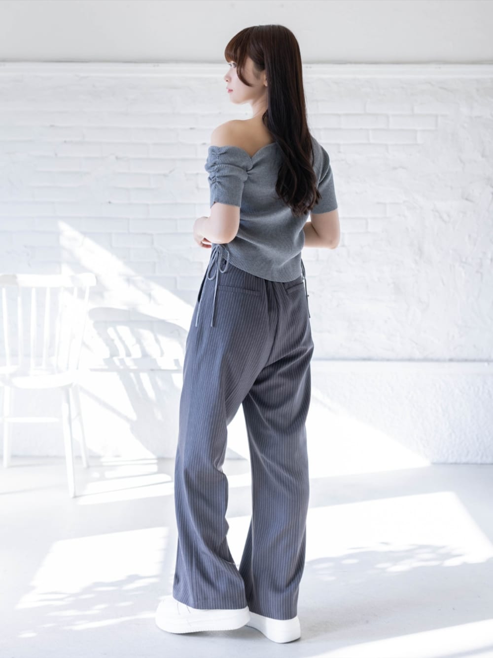 ホワイト系のスニーカー、グレー系のスラックス、グレー系のニット/セーターを着用したレディースの春コーディネートの2枚目の写真