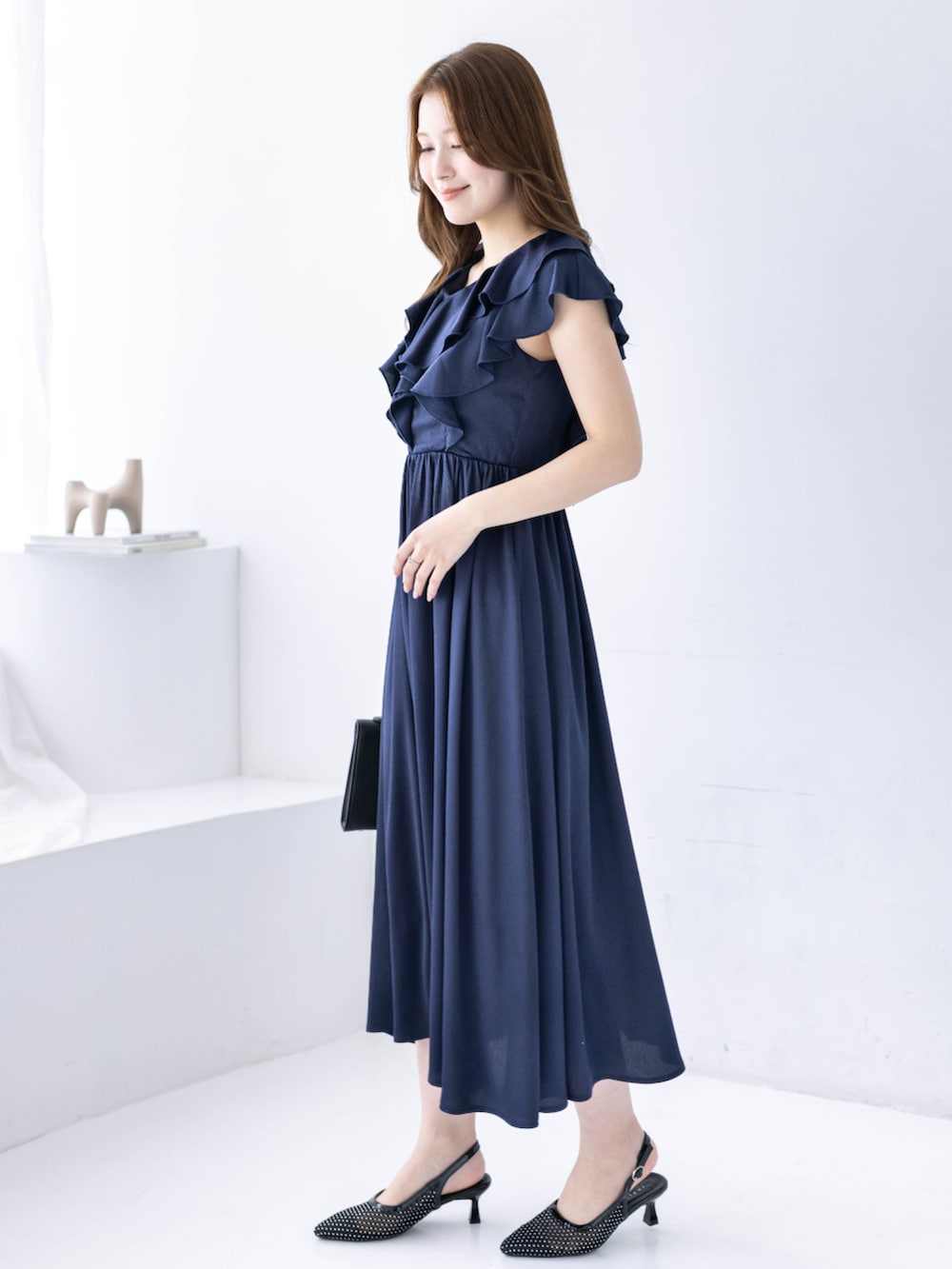 ブラック系のハンドバッグ、ブラック系のパンプス、ブルー系のワンピースを着用したレディースの春コーディネートの3枚目の写真