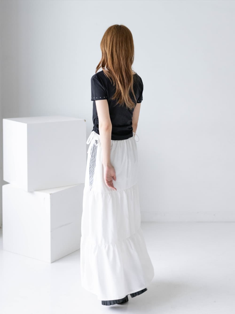 ブラック系のブーツ、ホワイト系のスカート、ブラック系のTシャツ/カットソーを着用したレディースの夏コーディネートの3枚目の写真