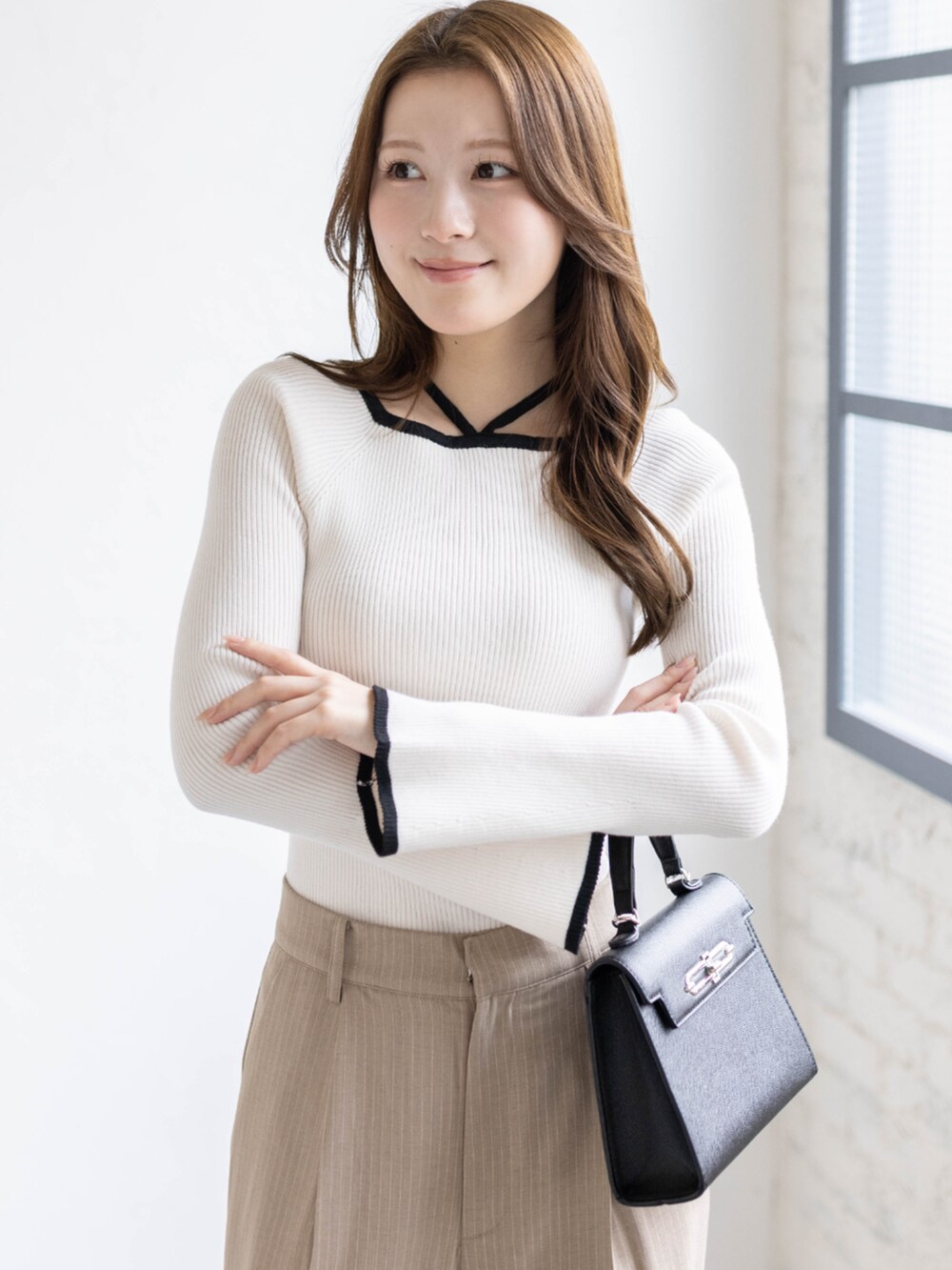 ホワイト系のニット/セーター、ベージュ系のスラックス、ブラック系のハンドバッグを着用したレディースの春コーディネートの4枚目の写真