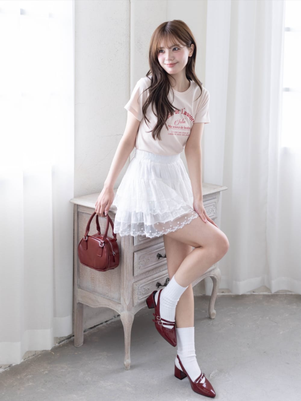 レッド系のパンプス、ピンク系のTシャツ/カットソー、ホワイト系のスカートを着用したレディースの春コーディネートの5枚目の写真