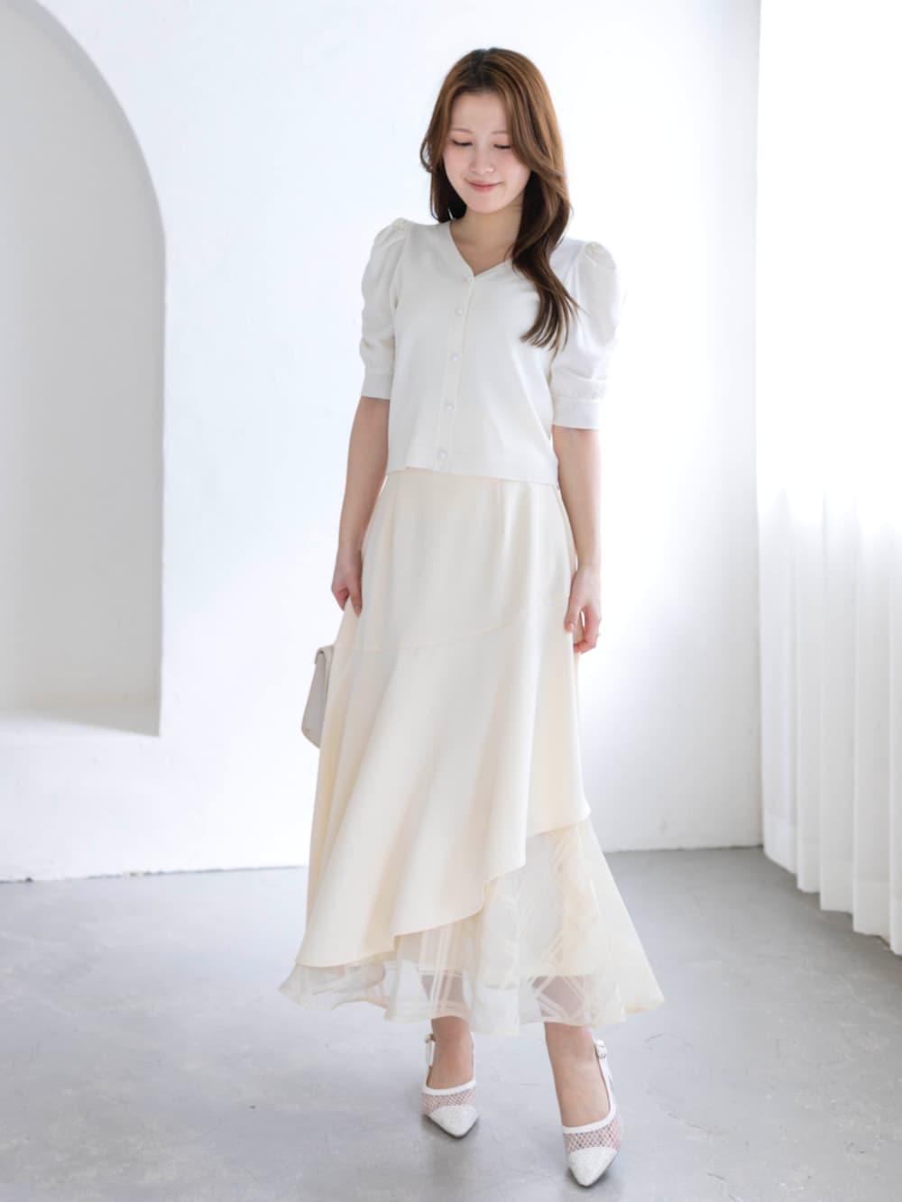 ホワイト系のスカート、ホワイト系のハンドバッグ、ホワイト系のパンプスを着用したレディースの春コーディネートの2枚目の写真