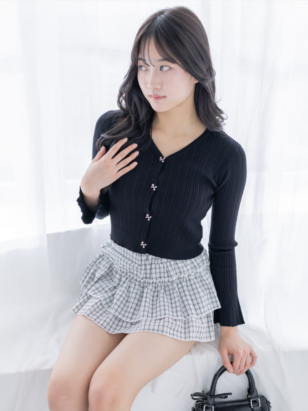 ブラック系のパンプス、ブラック系のハンドバッグ、ホワイト系のスカートを着用したレディースの夏コーディネートの6枚目の写真