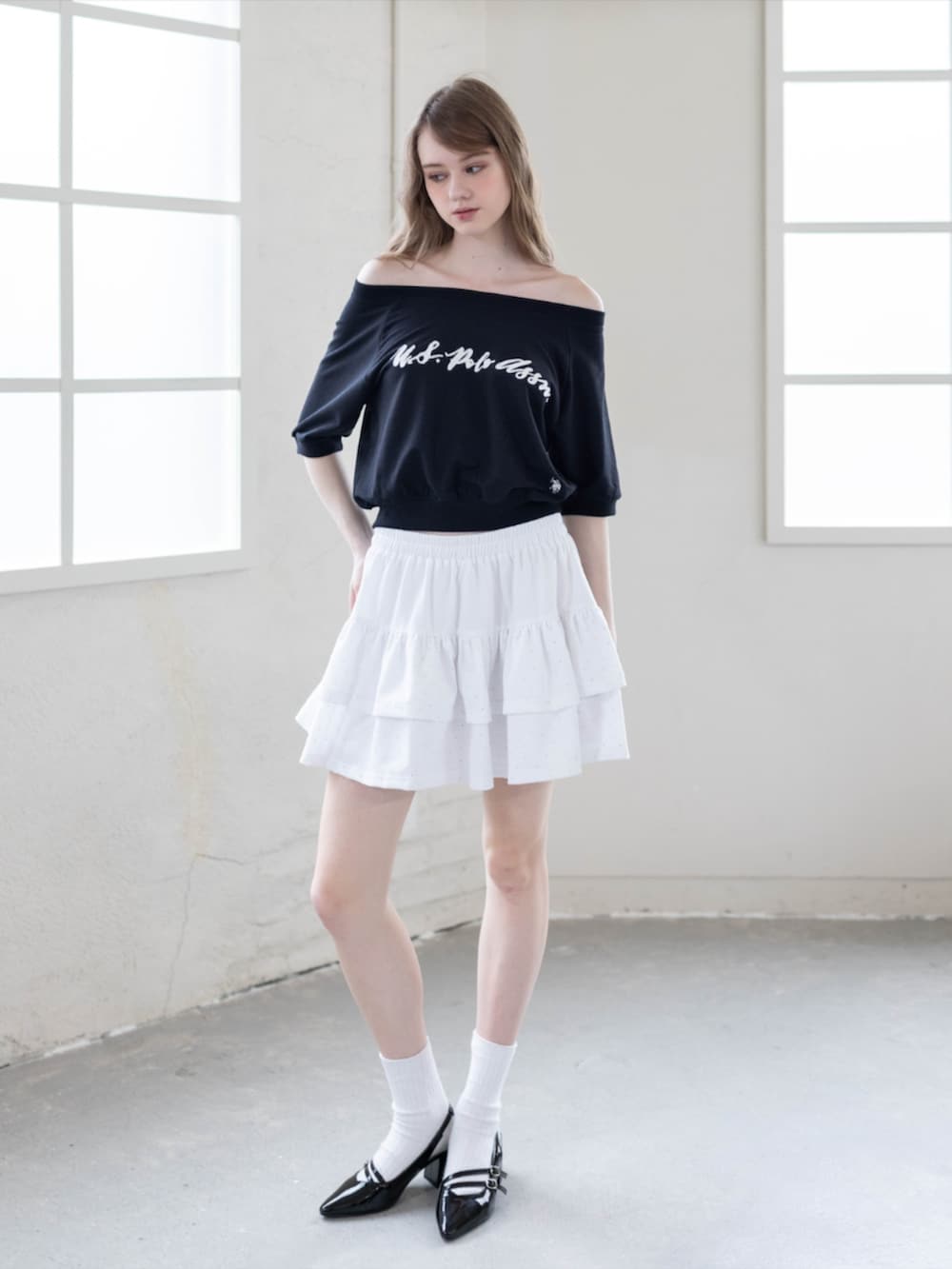 ブラック系のパンプス、ホワイト系のスカート、ブラック系のTシャツ/カットソーを着用したレディースの夏コーディネートの3枚目の写真