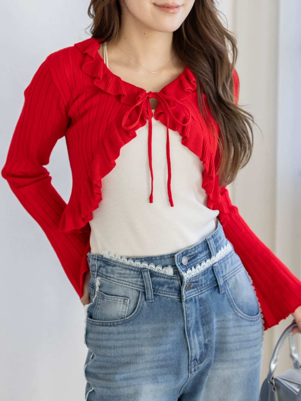 ブルー系のデニムパンツ、レッド系のカーディガン/ボレロを着用したレディースの冬コーディネートの4枚目の写真