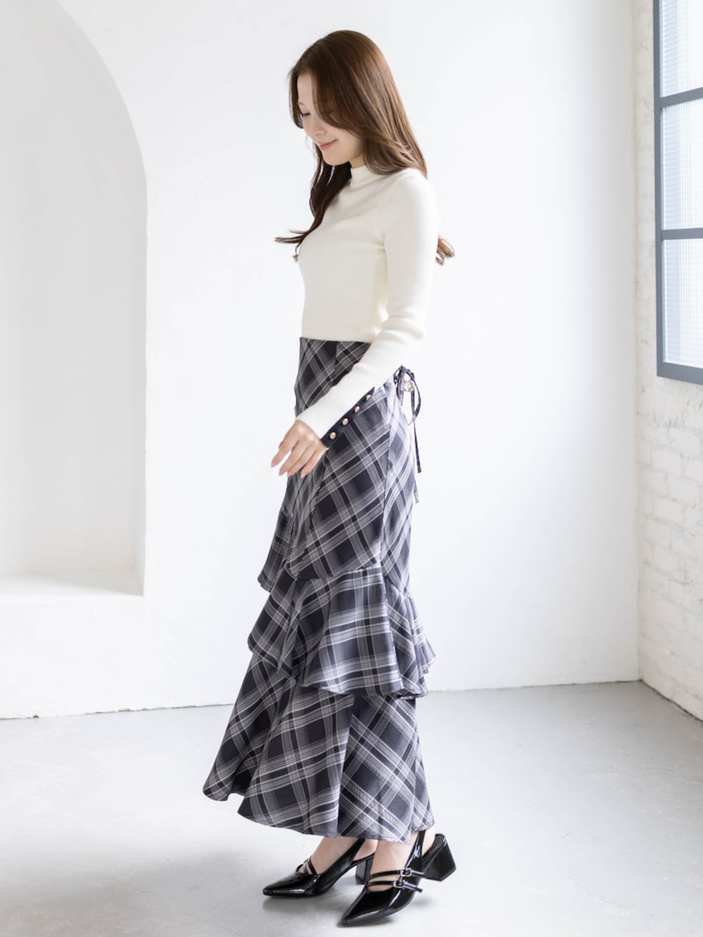 ブラック系のパンプス、ホワイト系のニット/セーター、ブラック系のスカートを着用したレディースの春コーディネートの2枚目の写真