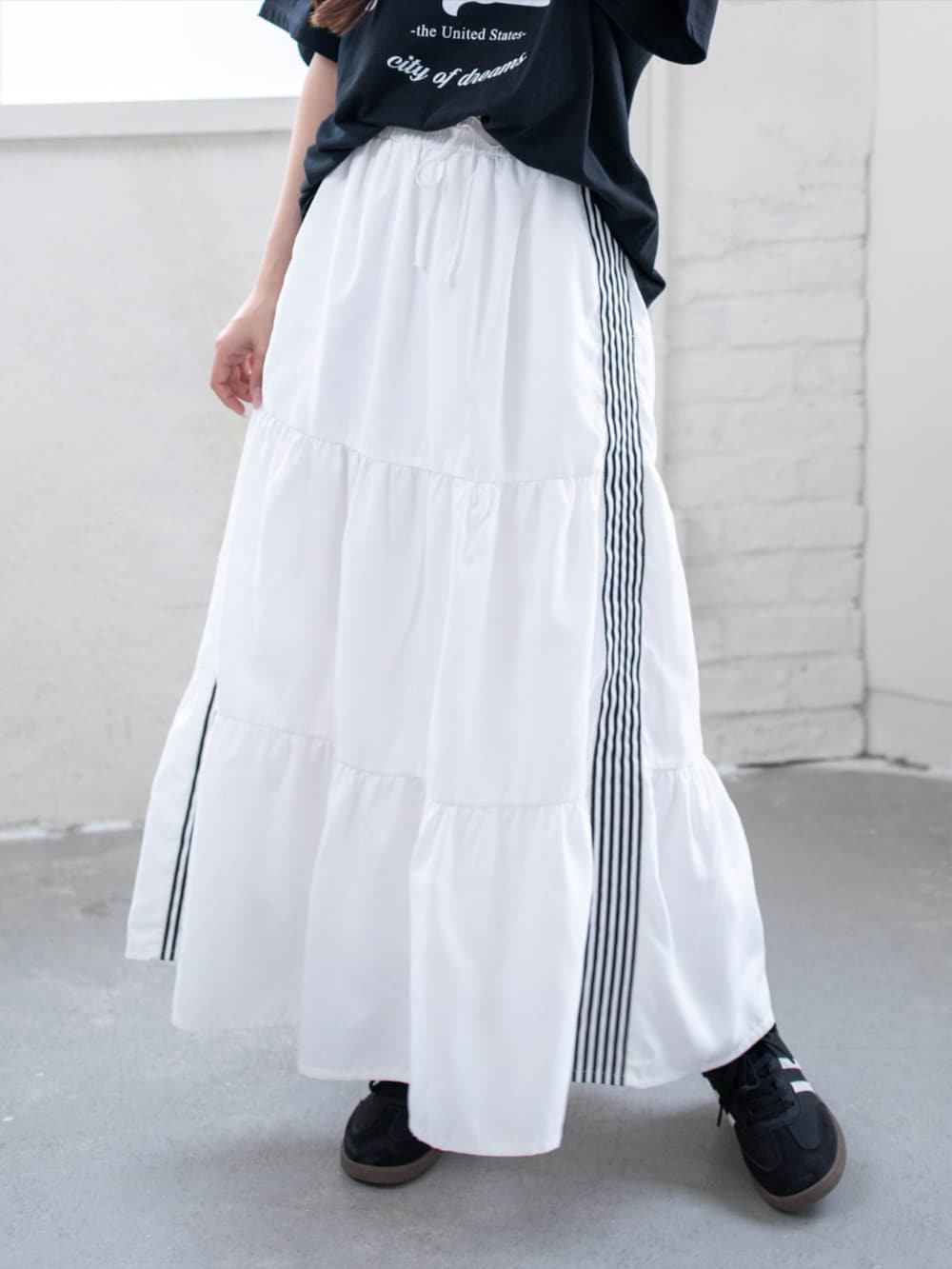 ブラック系のスニーカー、ホワイト系のスカート、ブラック系のTシャツ/カットソーを着用したレディースの夏コーディネートの7枚目の写真