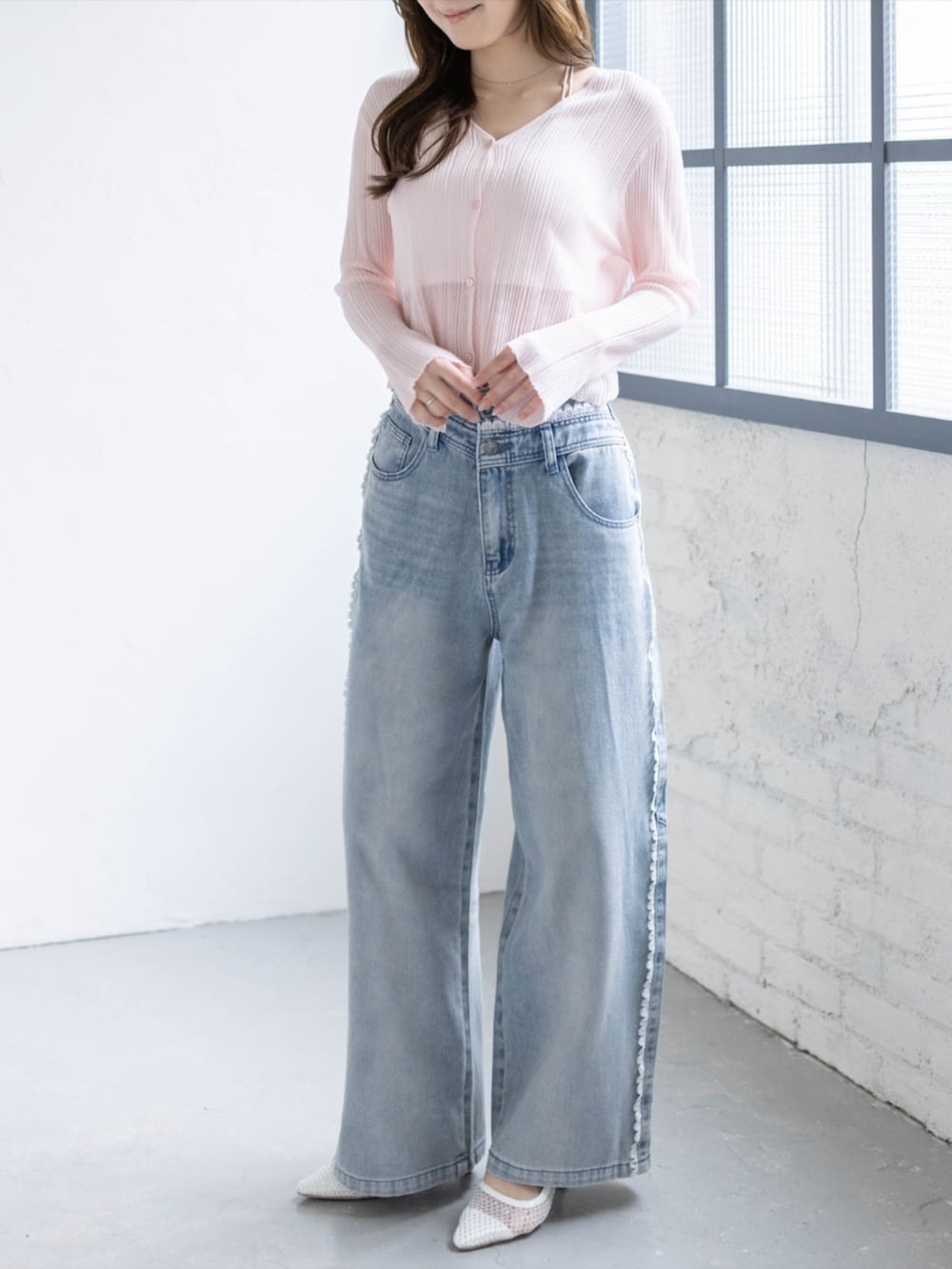 ブルー系のデニムパンツ、ホワイト系のパンプス、ピンク系のカーディガン/ボレロを着用したレディースの春コーディネートの2枚目の写真