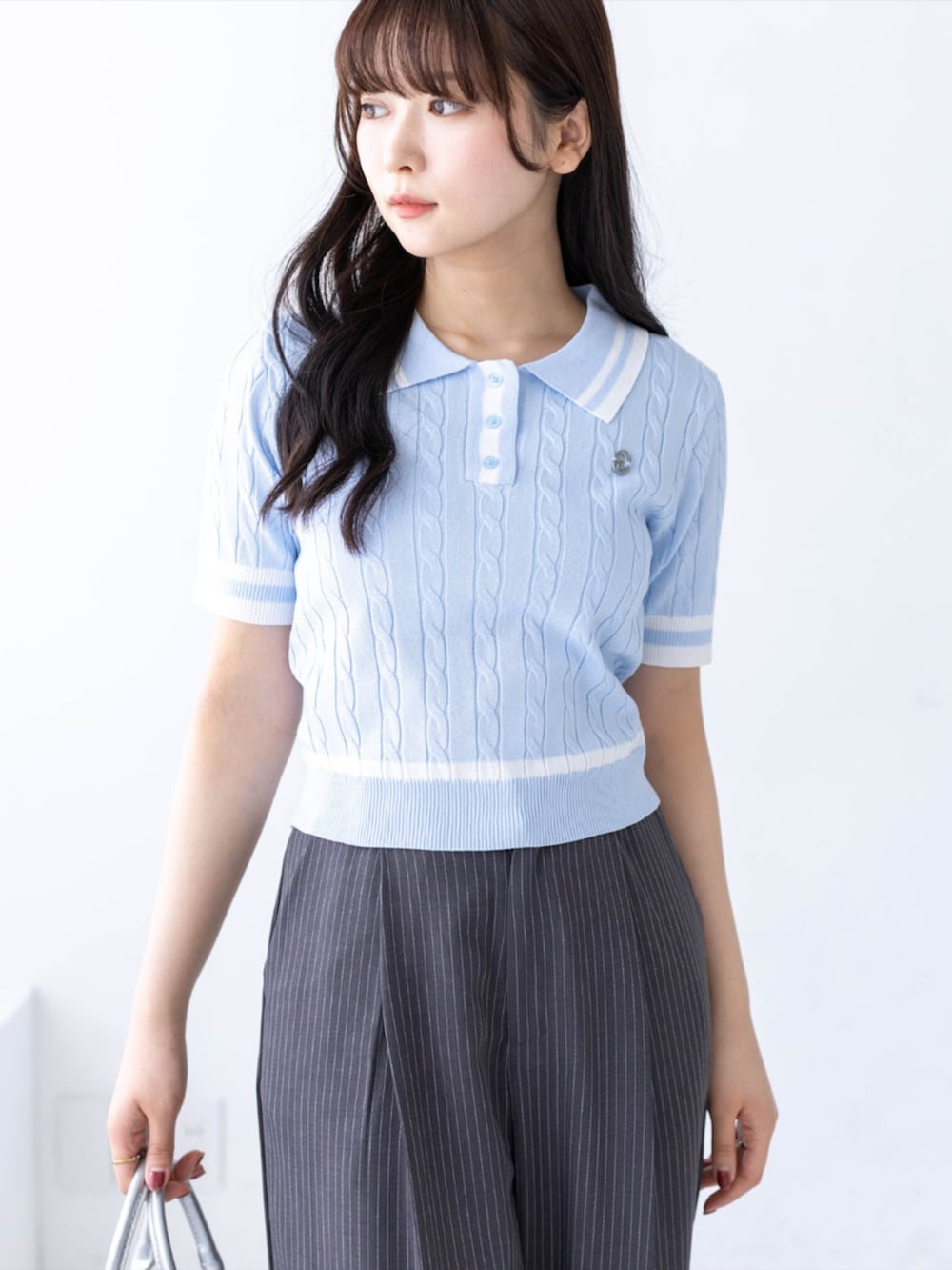 シルバー系のハンドバッグ、シルバー系のパンプス、グレー系のスラックスを着用したレディースの春コーディネートの4枚目の写真