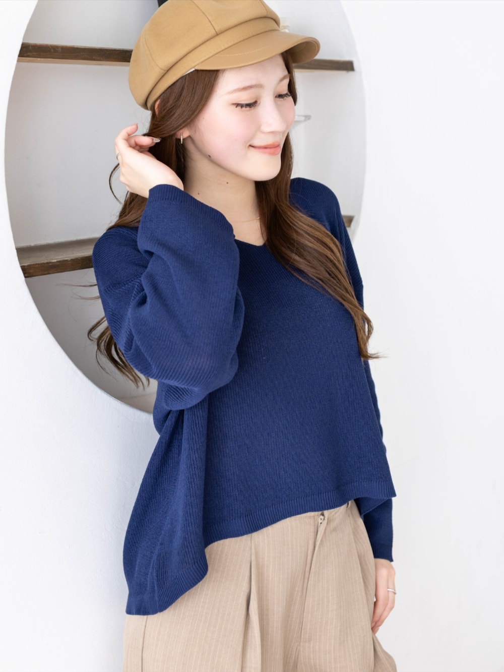 ホワイト系のスニーカー、ベージュ系のスラックス、ブルー系のニット/セーターを着用したレディースの春コーディネートの4枚目の写真