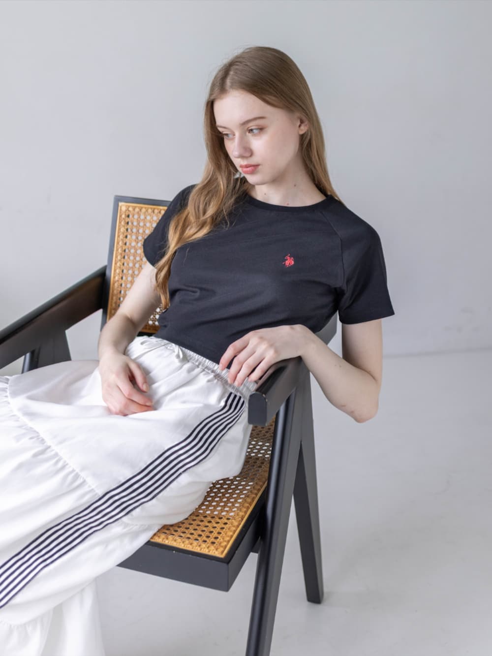 ブラック系のスニーカー、ホワイト系のスカート、ブラック系のTシャツ/カットソーを着用したレディースの夏コーディネートの7枚目の写真