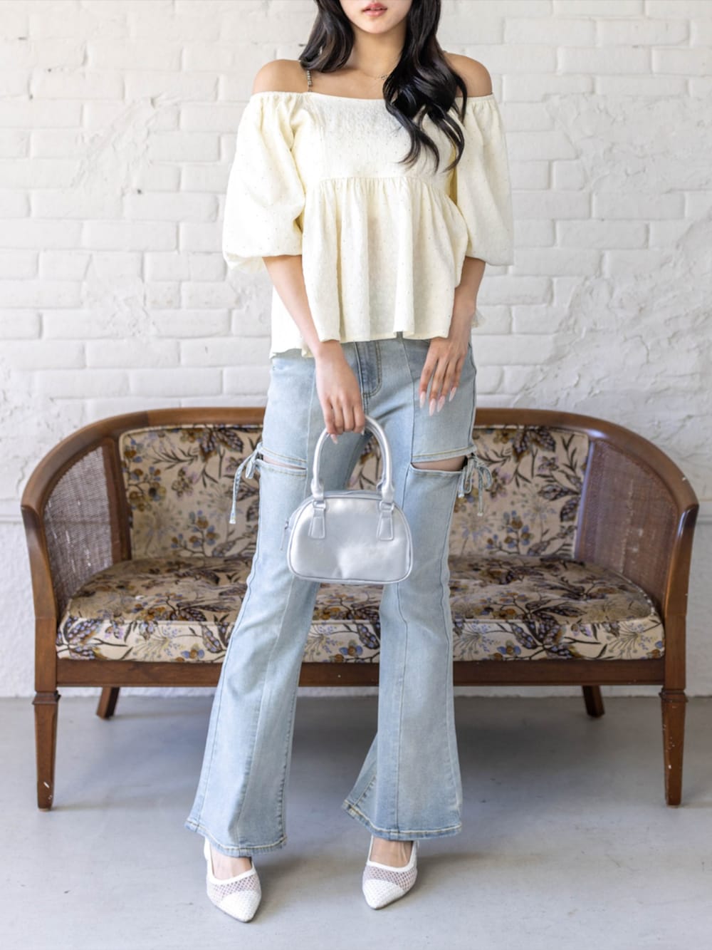シルバー系のハンドバッグ、ホワイト系のパンプス、ブルー系のデニムパンツを着用したレディースの春コーディネートの2枚目の写真