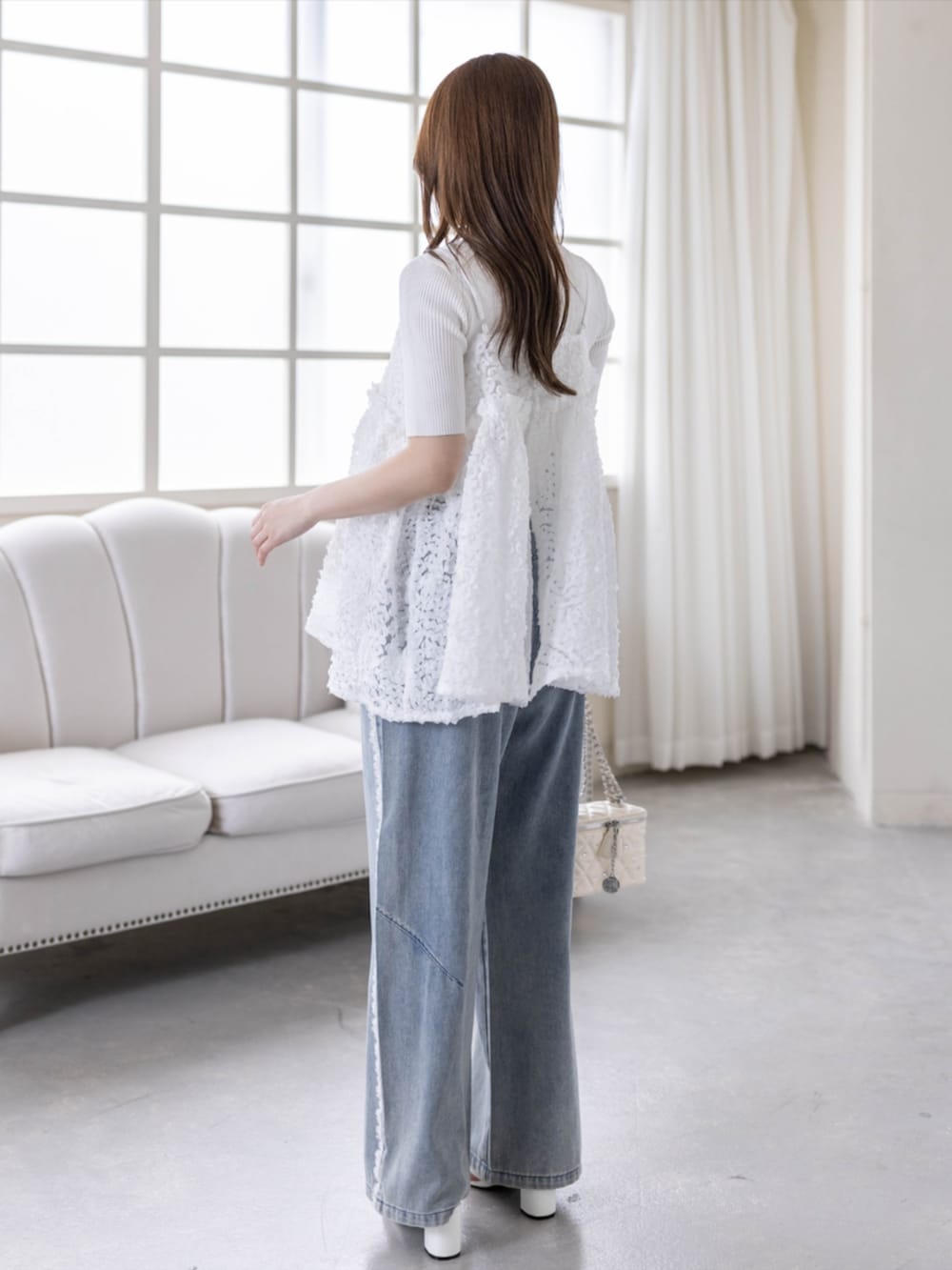 ホワイト系のニット/セーター、ブルー系のデニムパンツ、ホワイト系のサンダルを着用したレディースの春コーディネートの3枚目の写真