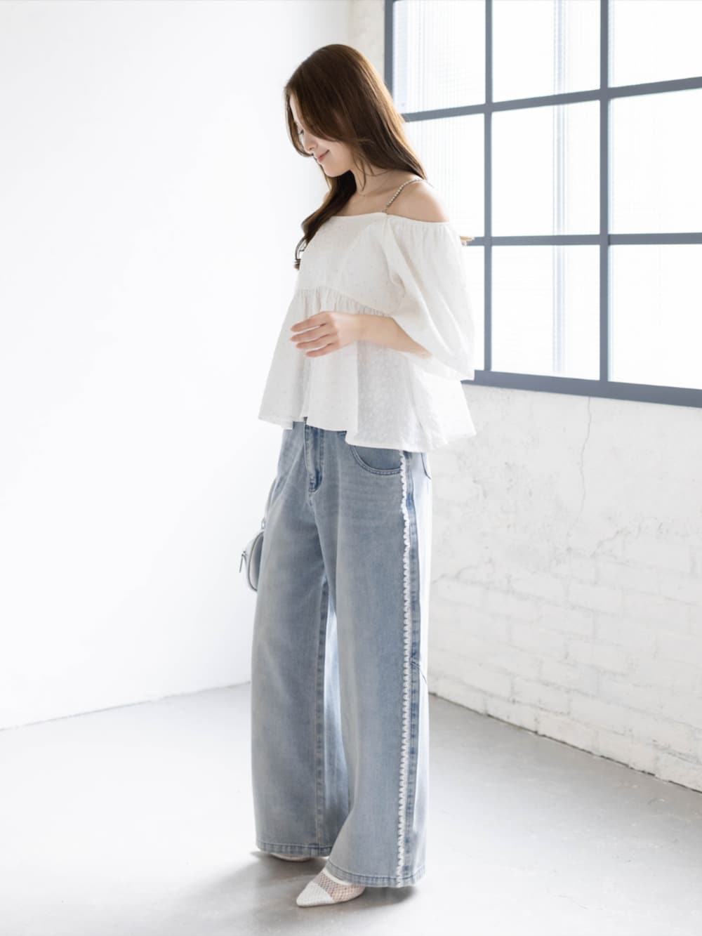 ブルー系のデニムパンツ、ホワイト系のパンプス、ホワイト系のシャツ/ブラウスを着用したレディースの夏コーディネートの3枚目の写真