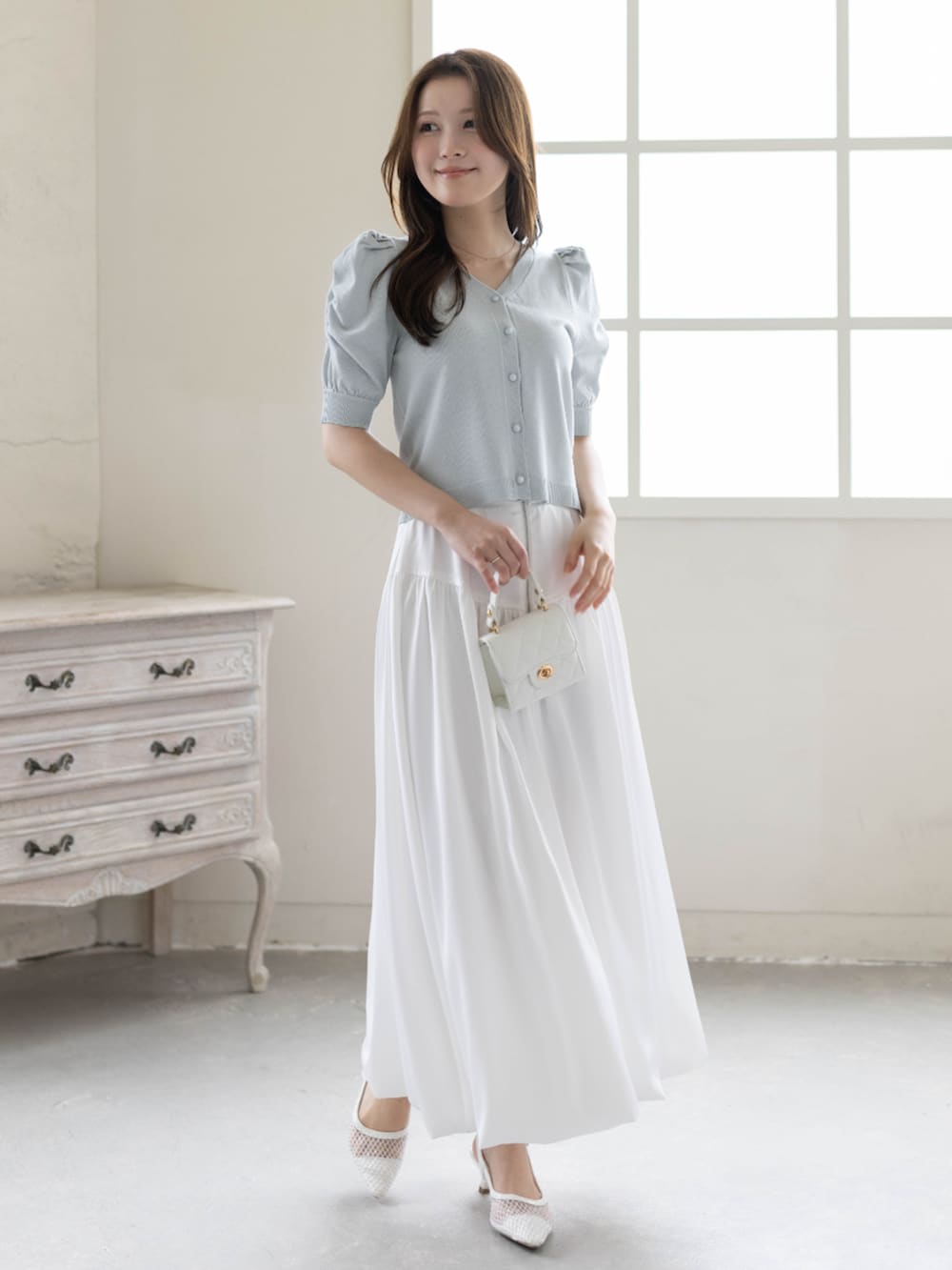 ホワイト系のスカート、ホワイト系のパンプス、グレー系のカーディガン/ボレロを着用したレディースの春コーディネートの2枚目の写真