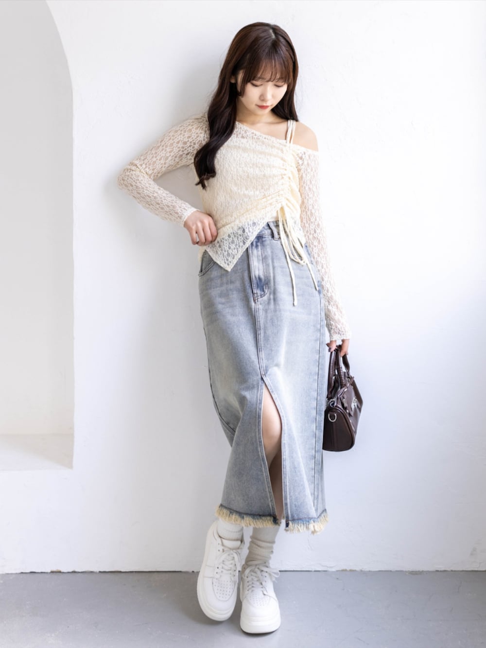 ブラウン系のボストンバッグ、ホワイト系のスニーカー、ブルー系のスカートを着用したレディースの春コーディネートの2枚目の写真