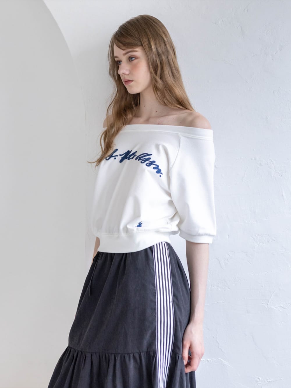 ブラック系のスニーカー、ブラック系のスカート、ホワイト系のTシャツ/カットソーを着用したレディースの夏コーディネートの4枚目の写真