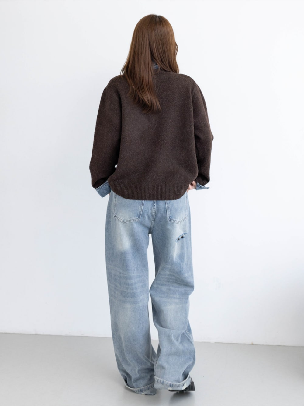 ブルー系のデニムパンツ、ブラック系のブーツ、ブラウン系のニット/セーターを着用したレディースの秋コーディネートの2枚目の写真