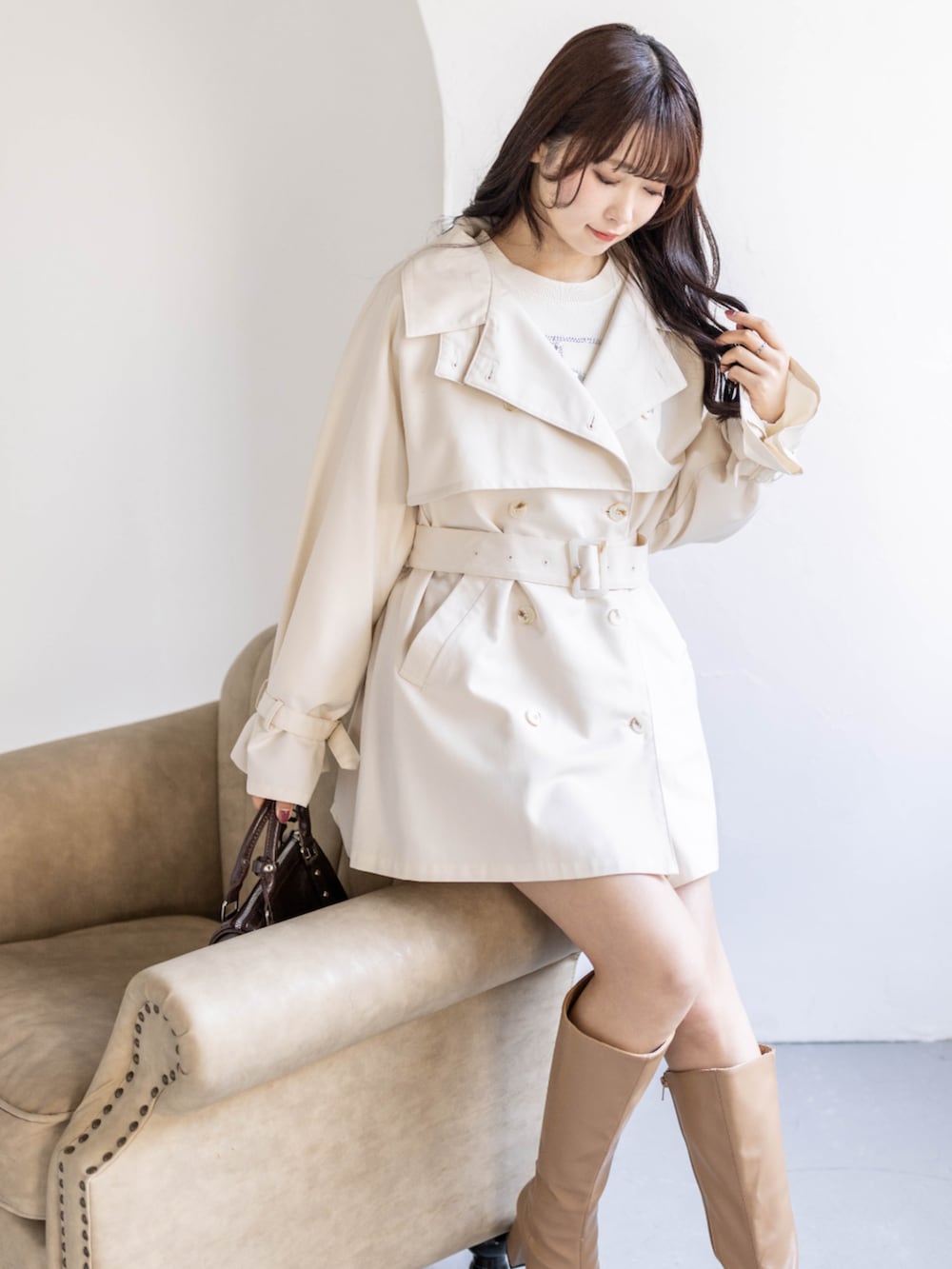 ベージュ系のブーツ、ホワイト系のトレンチコート、ホワイト系のニット/セーターを着用したレディースの春コーディネートの5枚目の写真