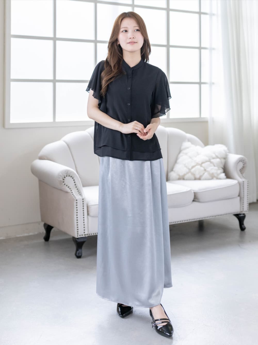 ブラック系のパンプス、ブラック系のシャツ/ブラウス、グレー系のスカートを着用したレディースの春コーディネートの2枚目の写真