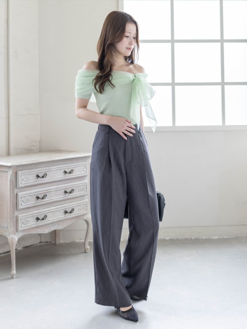 ブラック系のボストンバッグ、ブラック系のパンプス、グレー系のスラックスを着用したレディースの春コーディネートの2枚目の写真