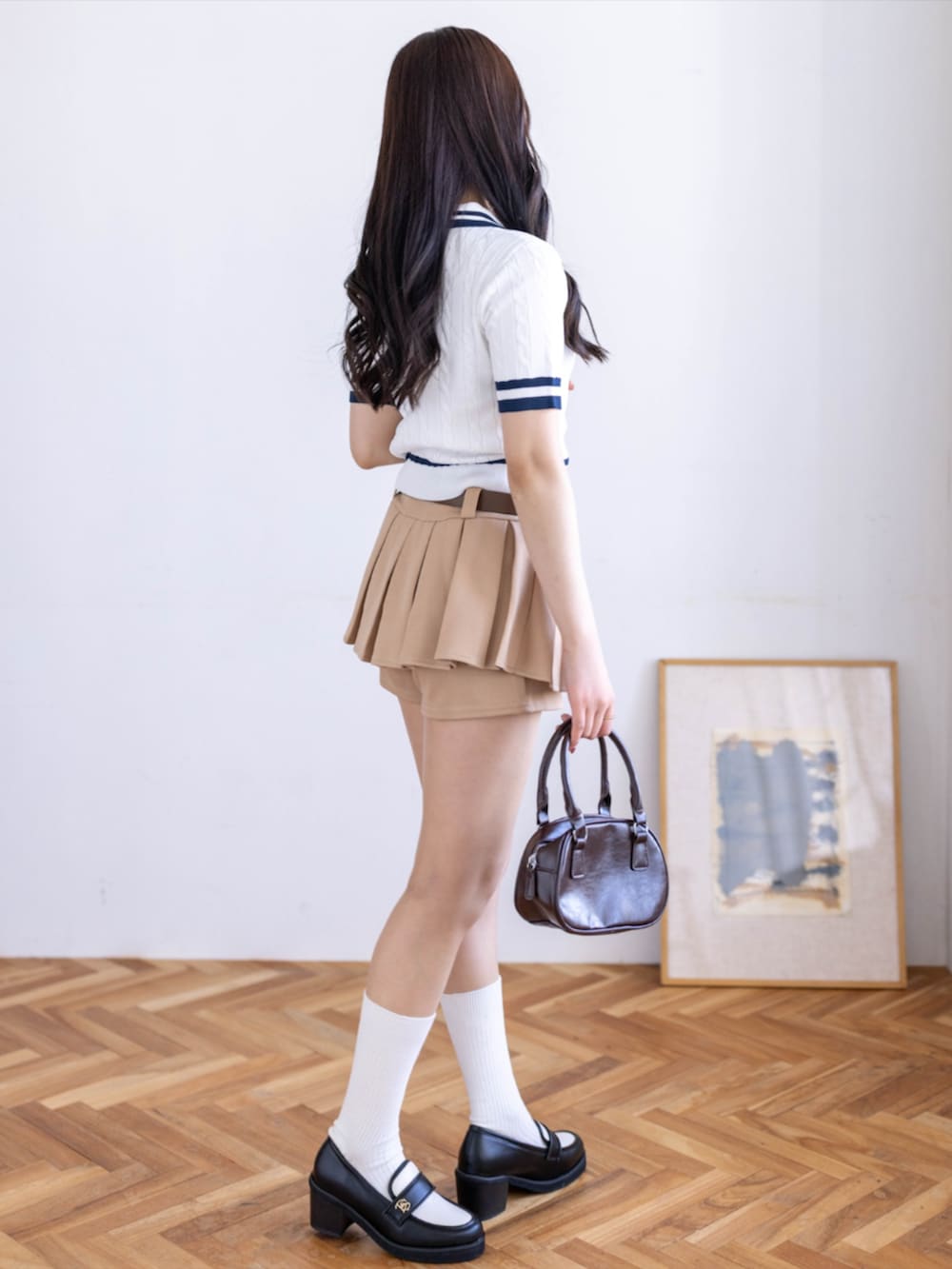 ブラウン系のハンドバッグ、ベージュ系のスカート、ブラック系のローファーを着用したレディースの春コーディネートの2枚目の写真