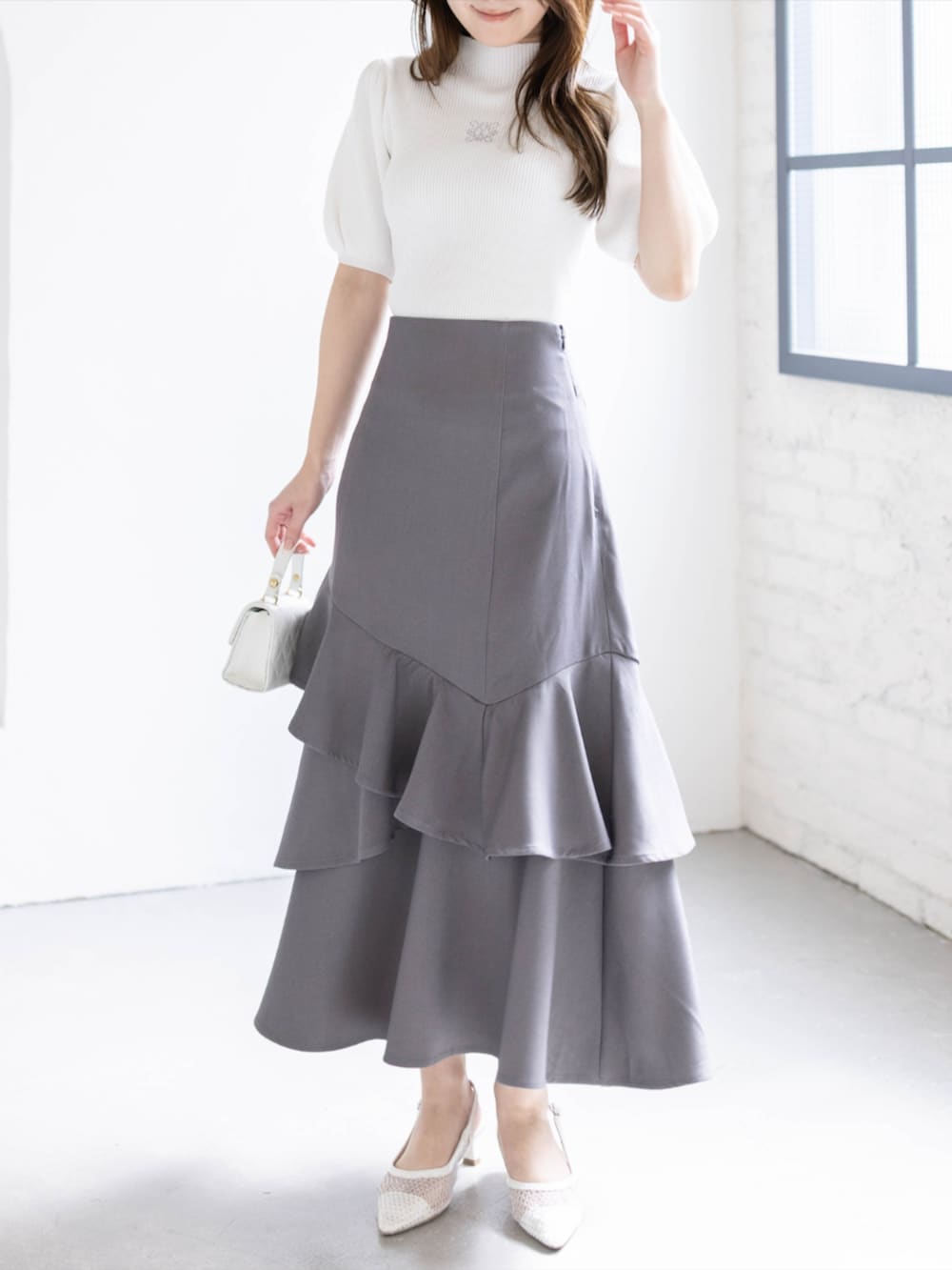 ホワイト系のパンプス、ホワイト系のニット/セーター、グレー系のスカートを着用したレディースの春コーディネートの4枚目の写真