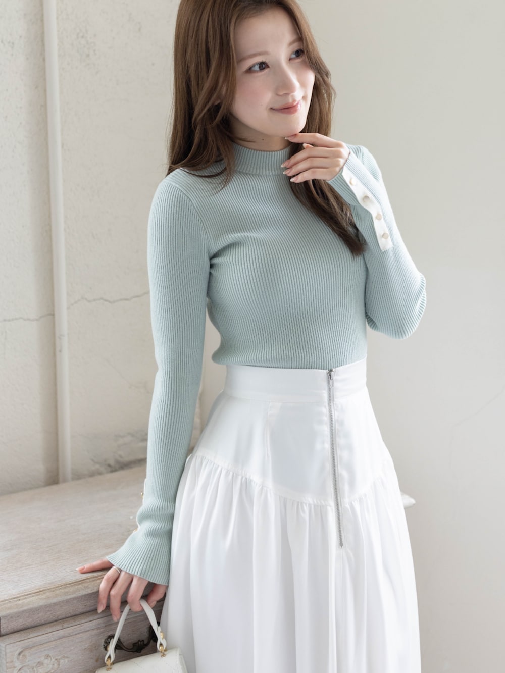 グリーン系のニット/セーター、ホワイト系のスカート、ホワイト系のパンプスを着用したレディースの春コーディネートの5枚目の写真