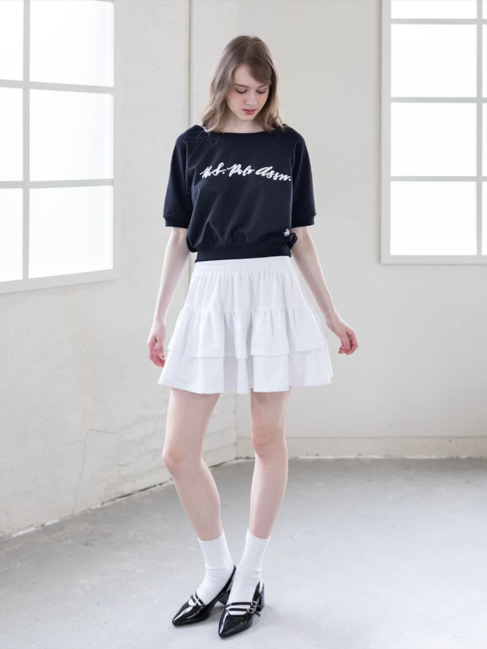 ブラック系のパンプス、ホワイト系のスカート、ブラック系のTシャツ/カットソーを着用したレディースの夏コーディネートの2枚目の写真