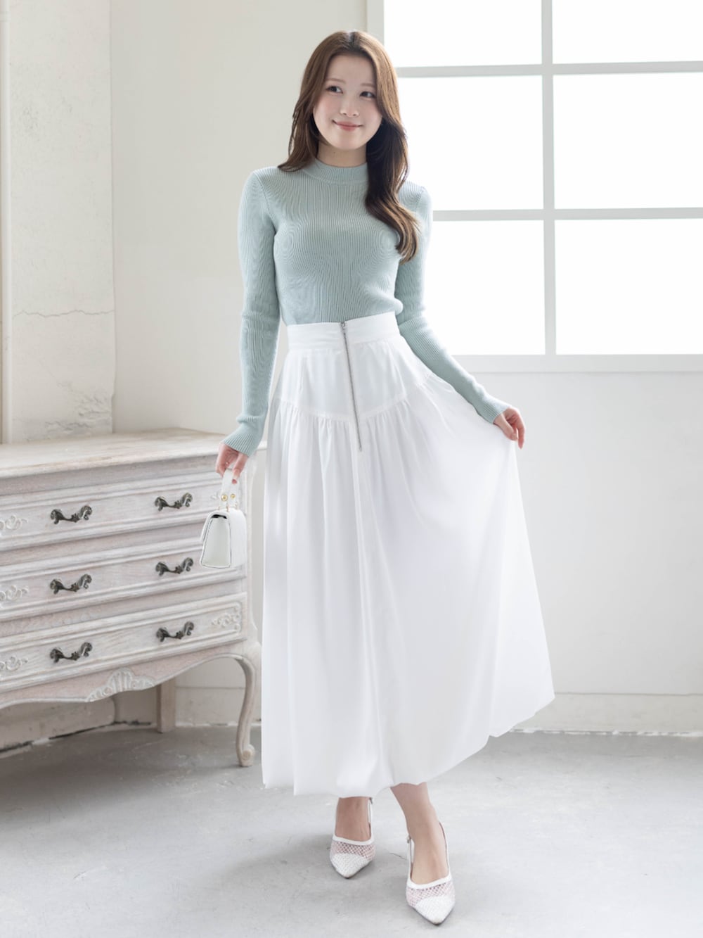 グリーン系のニット/セーター、ホワイト系のスカート、ホワイト系のパンプスを着用したレディースの春コーディネートの3枚目の写真
