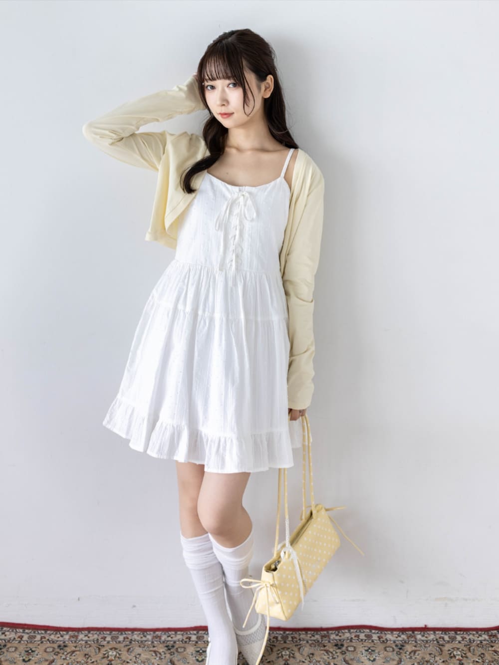 ホワイト系のワンピース、ホワイト系のパンプス、イエロー系のカーディガン/ボレロを着用したレディースの夏コーディネートの4枚目の写真