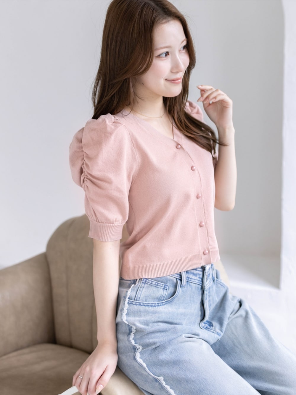 ブルー系のデニムパンツ、ホワイト系のパンプス、ピンク系のカーディガン/ボレロを着用したレディースの春コーディネートの5枚目の写真