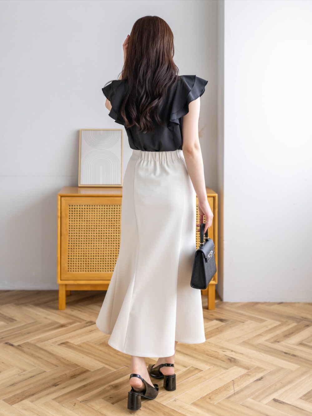 ブラック系のパンプス、ホワイト系のスカート、ホワイト系のハンドバッグを着用したレディースの夏コーディネートの2枚目の写真