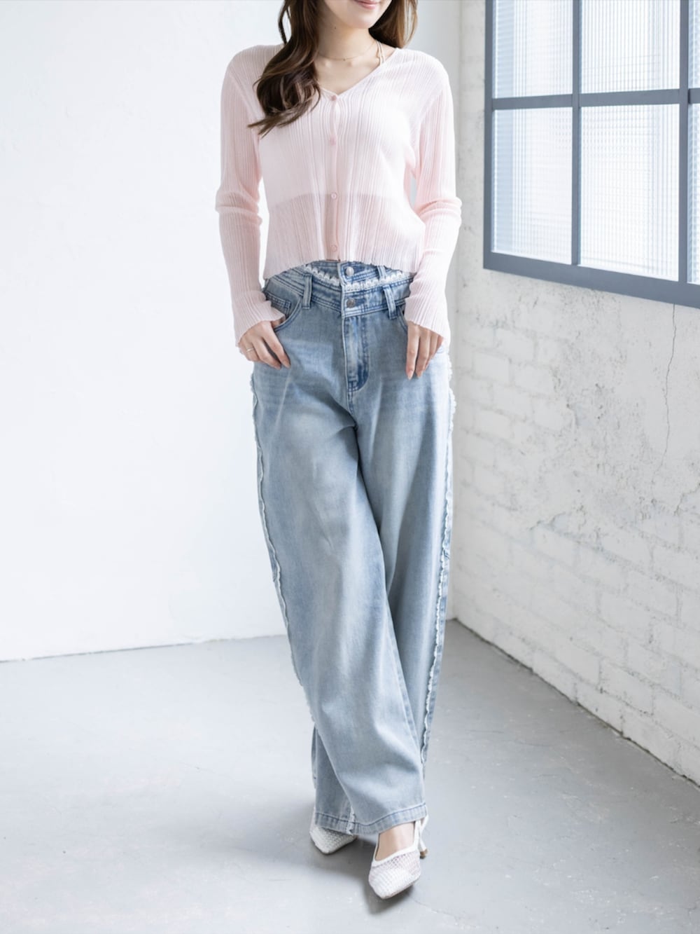 ブルー系のデニムパンツ、ホワイト系のパンプス、ピンク系のカーディガン/ボレロを着用したレディースの春コーディネートの3枚目の写真