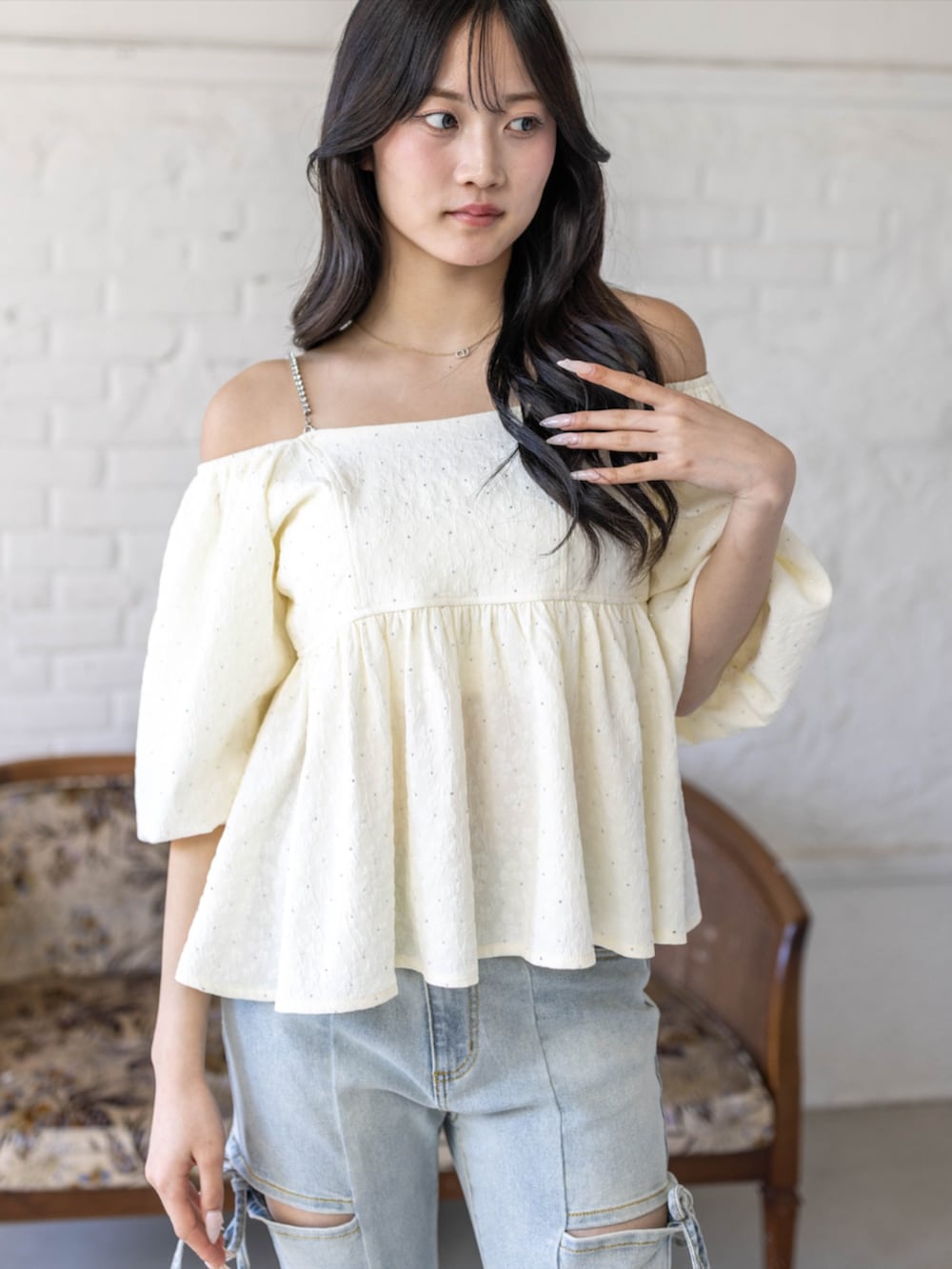 シルバー系のハンドバッグ、ホワイト系のパンプス、ブルー系のデニムパンツを着用したレディースの春コーディネートの4枚目の写真