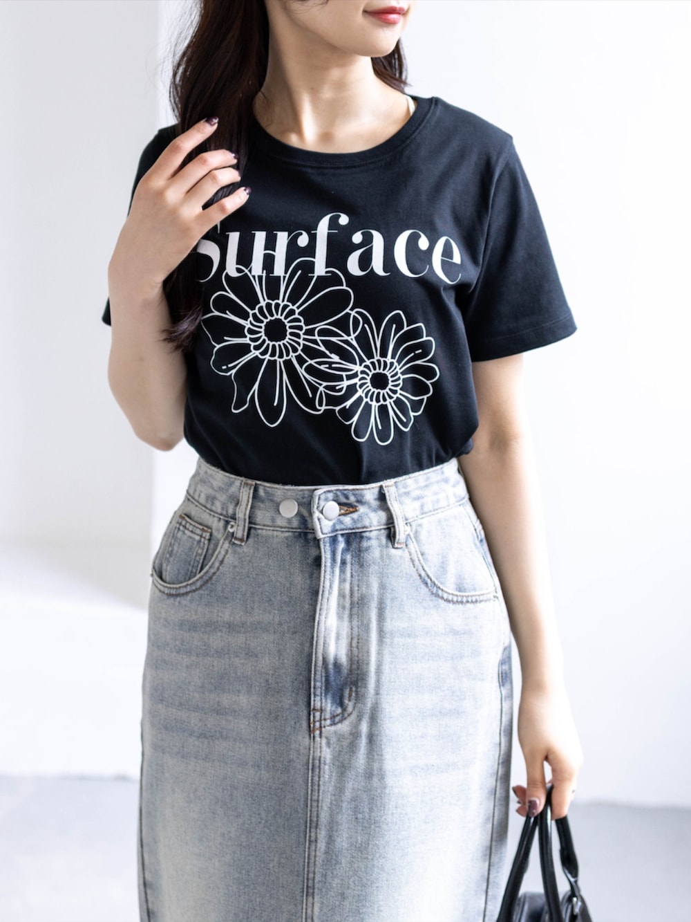 ホワイト系のスニーカー、ブルー系のスカート、ブラック系のTシャツ/カットソーを着用したレディースの春コーディネートの5枚目の写真