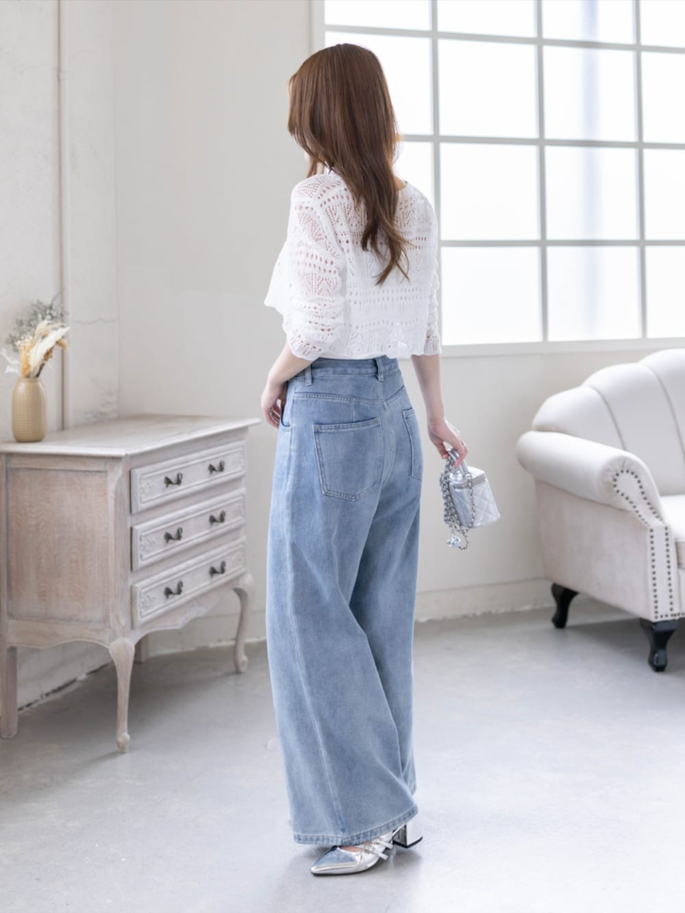 シルバー系のパンプス、ブルー系のデニムパンツ、ホワイト系のニット/セーターを着用したレディースの春コーディネートの2枚目の写真