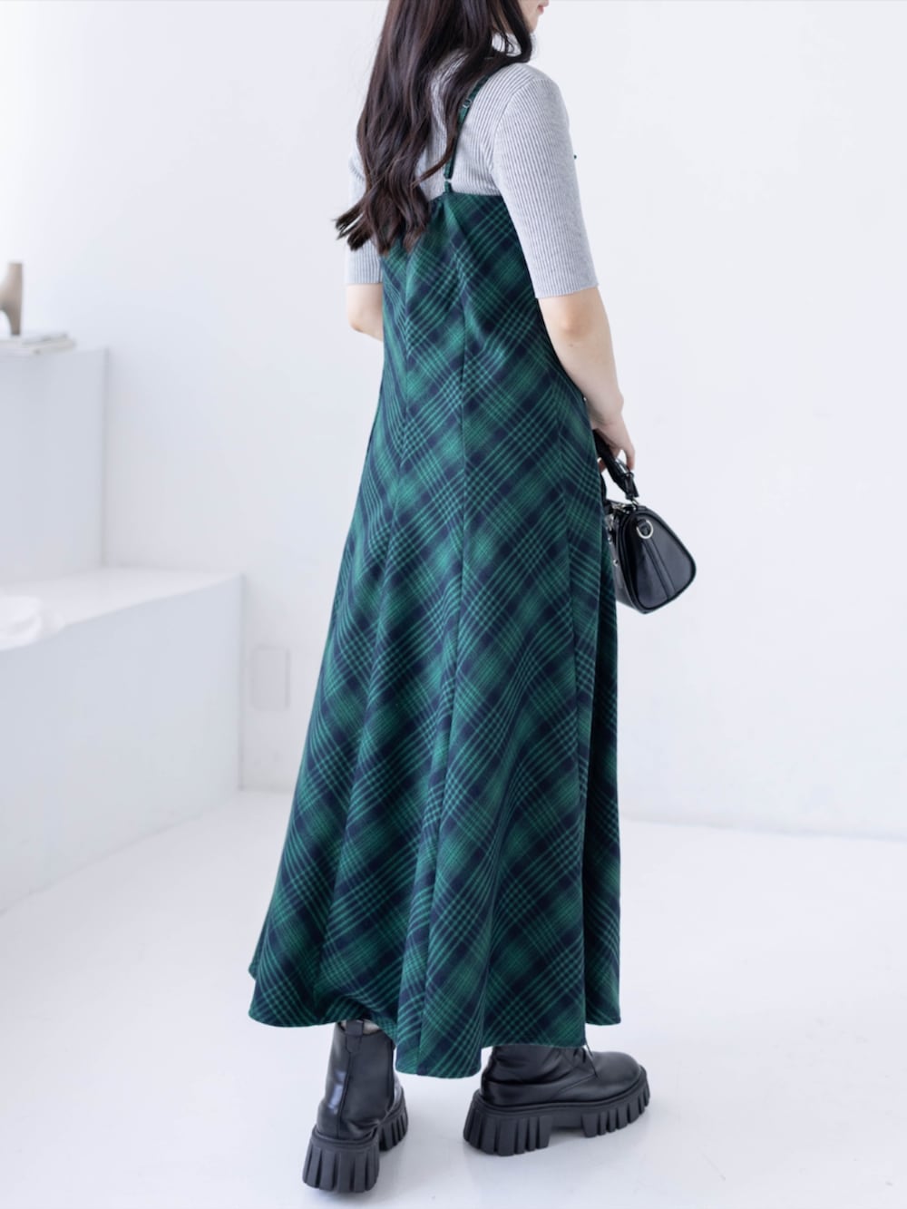 グレー系のニット/セーター、ブラック系のブーツ、グリーン系のワンピースを着用したレディースの春コーディネートの2枚目の写真