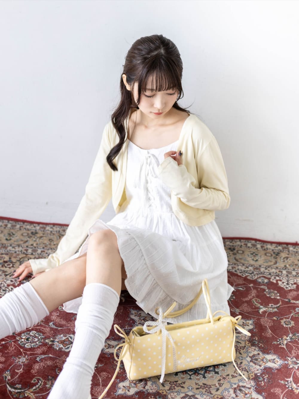 ホワイト系のワンピース、ホワイト系のパンプス、イエロー系のカーディガン/ボレロを着用したレディースの夏コーディネートの7枚目の写真