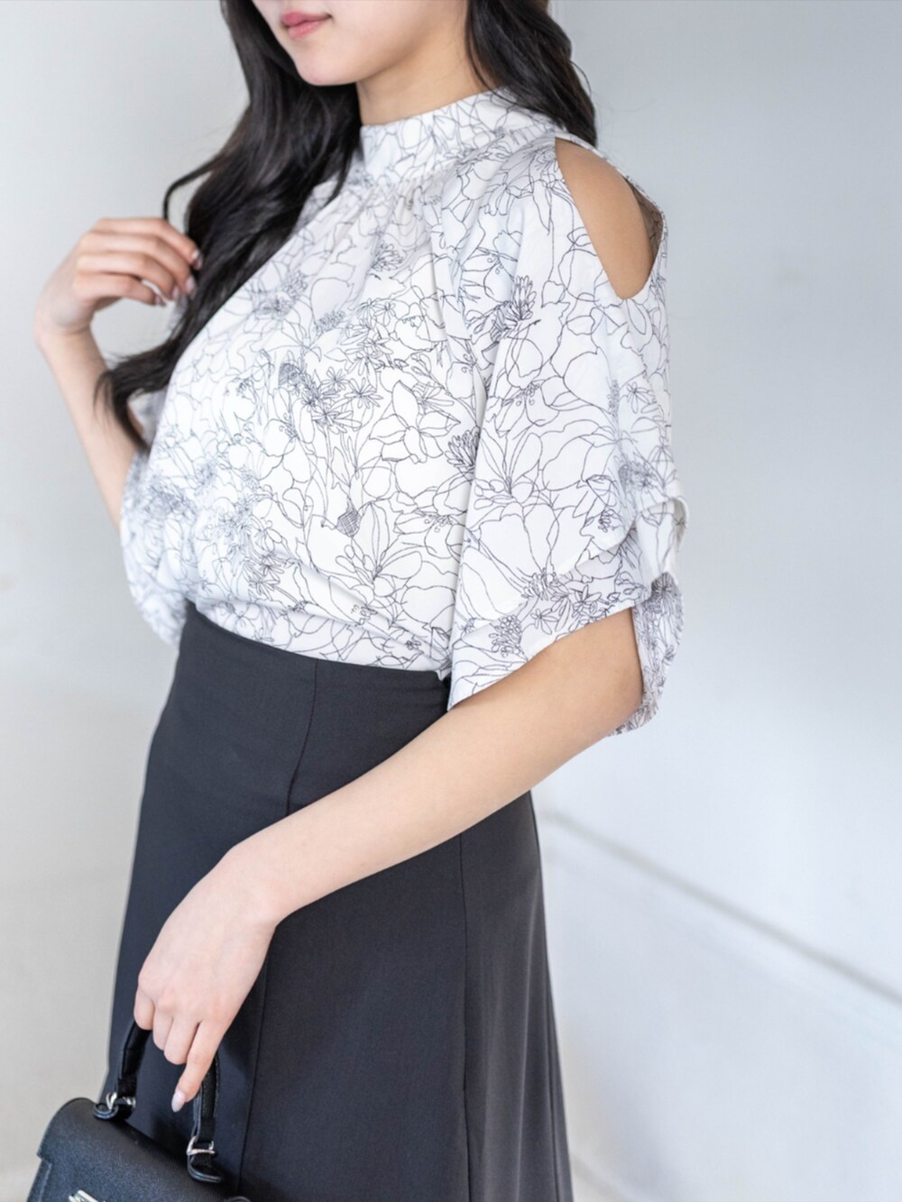 ブラック系のハンドバッグ、ブラック系のパンプス、ブラック系のスカートを着用したレディースの春コーディネートの4枚目の写真